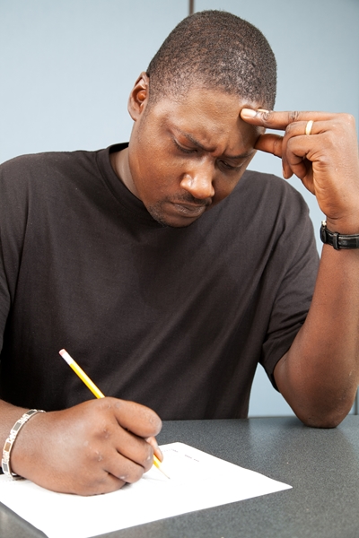 African-american adult education student struggles with test anxiety as he takes an exam.