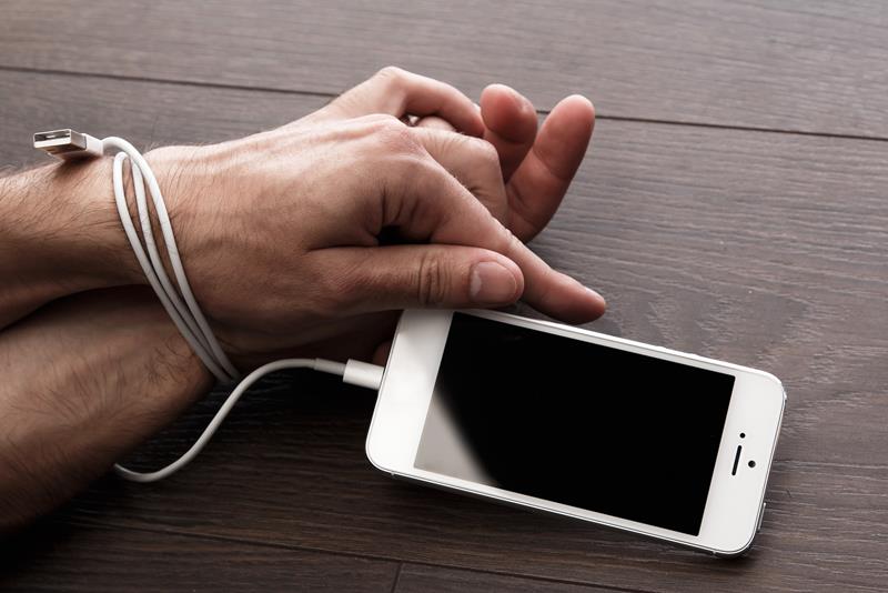 internet addiction represented by someone being handcuffed to smartphone